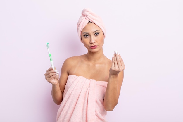 Asiatic pretty woman making capice or money gesture, telling you to pay. toothbrush concept