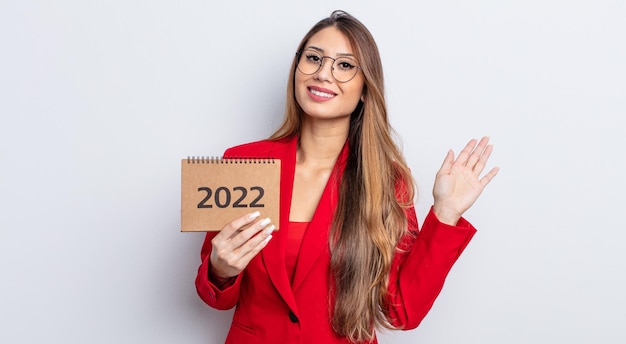 Asiatic pretty woman smiling happily waving hand welcoming and greeting you calendar concept