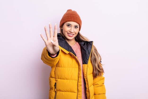 Asiatic pretty woman smiling and looking friendly, showing number four. winter concept