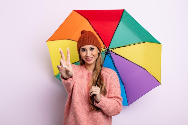 Asiatic pretty woman smiling and looking friendly, showing number two. umbrella concept