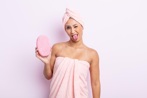 Asiatic pretty woman with cheerful and rebellious attitude, joking and sticking tongue out. bathrobe and sponge concept