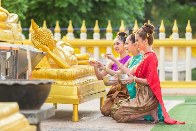 아시아 여자는 태국에서 행복하게 불상을 입욕하고 있습니다.