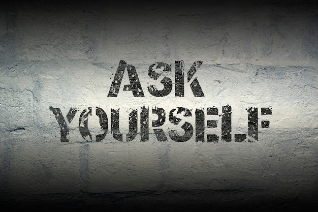 Ask yourself stencil print on the grunge white brick wall