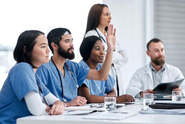 Asking probing questions about the problem Shot of a doctor raising his hand during a meeting in a hospital boardroom