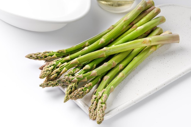 Asperges bereiden Verse groene asperges op wit keramisch bord en witte tafel