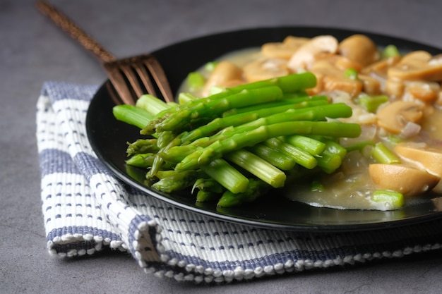 Asperges groen en paddestoel op plaat op zwarte ondergrond