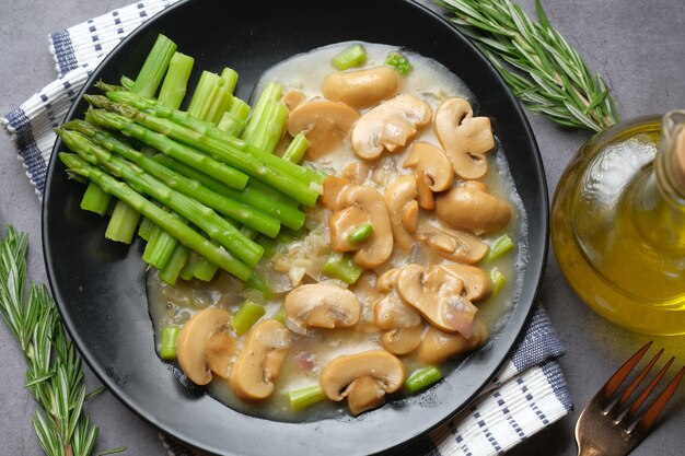 Asperges groene olijfolie en champignons op plaat zwart oppervlak