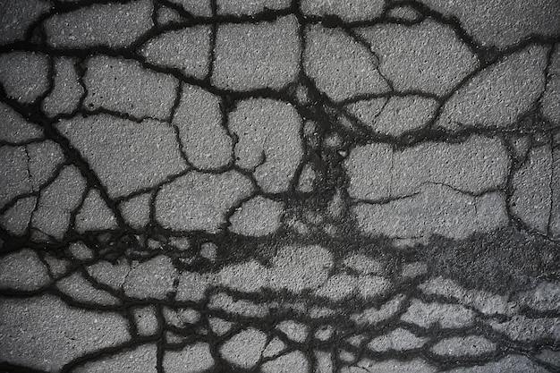 Asphalt in cracks texture / abstract background cracks on\
asphalt road