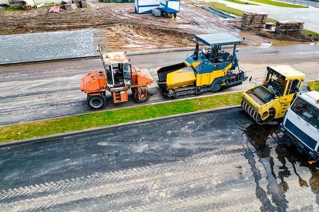 Asphalt laying equipment asphalt paver machine on the road\
repair site road renewal process construction work view from above\
drone photography