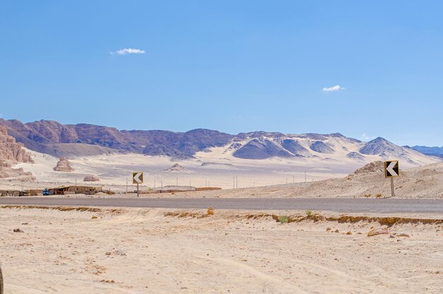 Asphalt motorway built in large desert with rocky mountains and hills of yellow sand beautiful wild