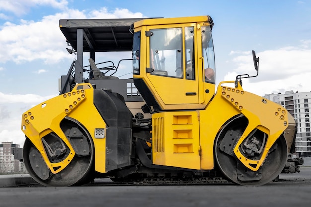 Photo asphalt paving machine and heavy vibratory roller closeup a paver finisher asphalt finisher or paving machine placing a layer of asphalt repaving the road surface road works