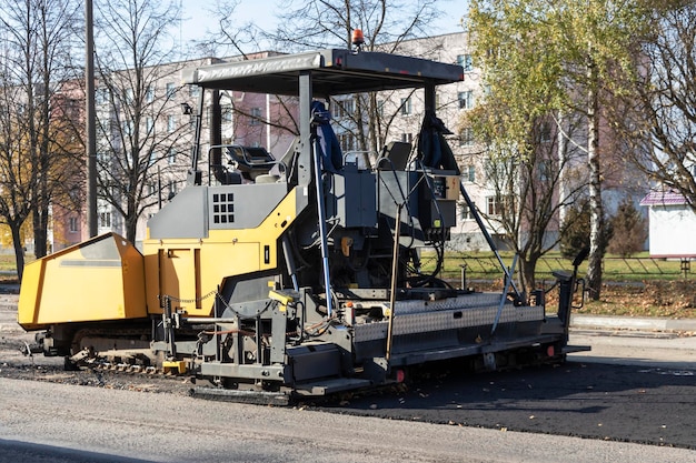 Photo an asphalt paving machine works in the city center in the fall. repair of road surfaces in a modern city using specialized equipment.