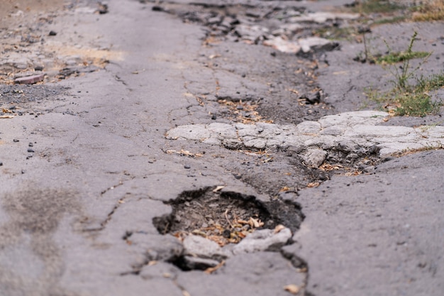 Asphalt road destroyed by holes and washed out by water