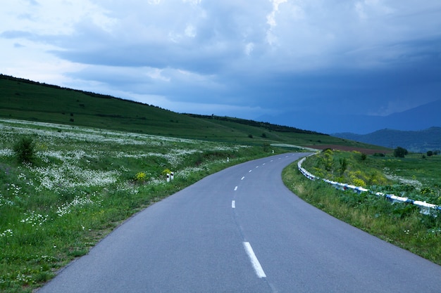 夕方、森の中の山腹をアスファルト道路が下ります