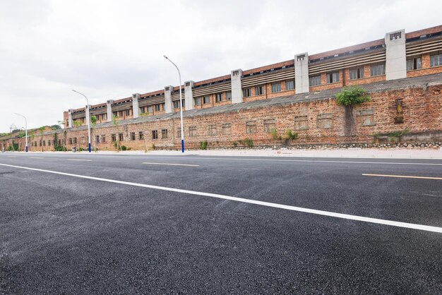 The asphalt road straight ahead of the old redbrick building