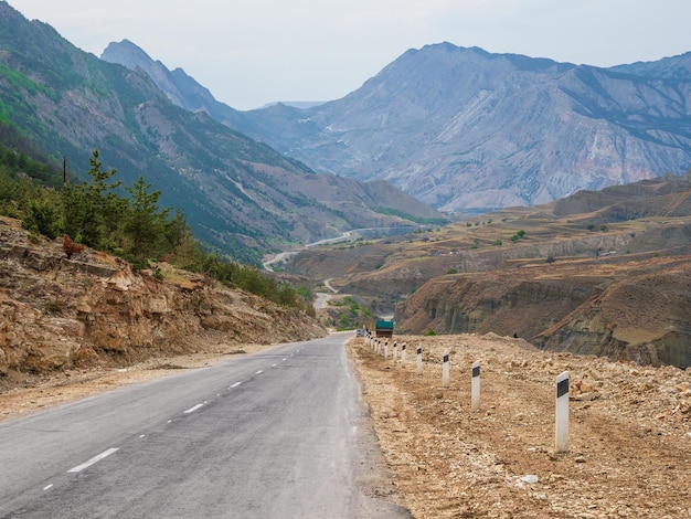 Asphalt road stretching into the distance.  Hot asphalt road through the hills and mountains. Turn on an empty mountain road. Old cracked asphalt mountain road in Dagestan.