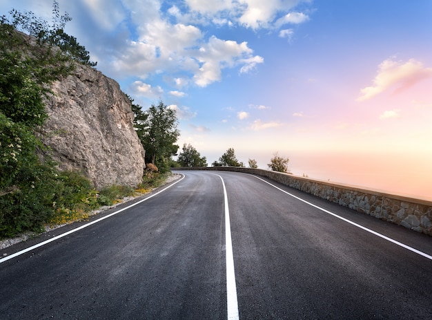 Asphalt road in summer forest at sunset. Crimean mountains