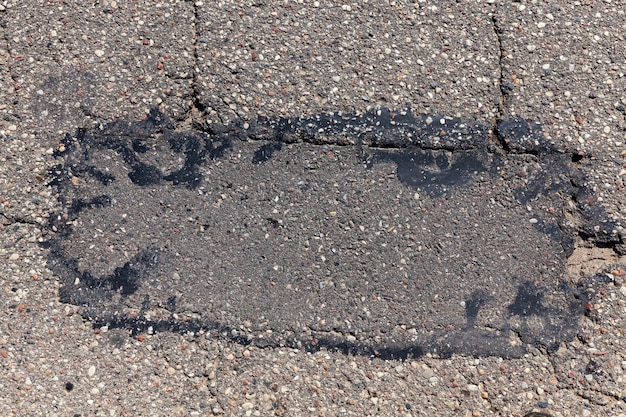 An asphalt road with a lot of holes and damage