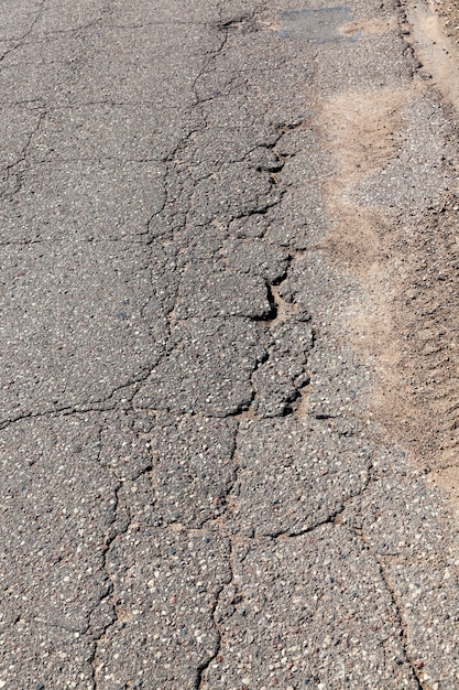 An asphalt road with a lot of holes and damage