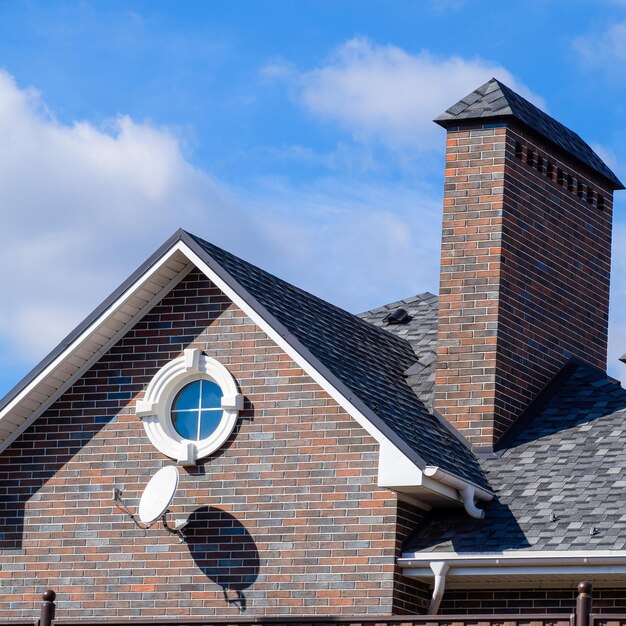 Photo asphalt shingle decorative bitumen shingles on the roof of a brick house