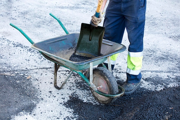 asphalt in wheelbarrow operator prepares mixture with uniform