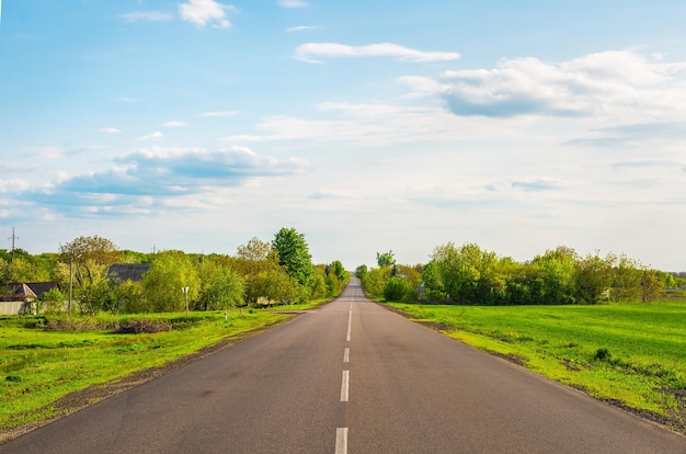 Asphalted road through countryside at spring sunset