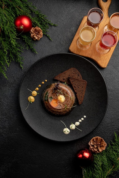 Холодец подается с черным хлебом на темной тарелке с горчицей и хреном на темном рождественском фоне