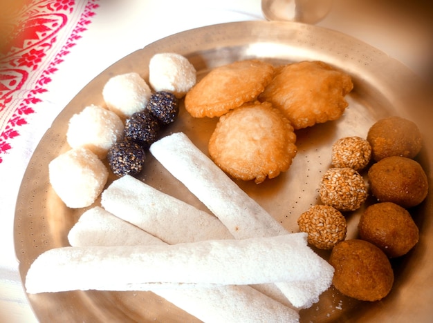 Assamese traditional food items like pitha laddu doi sira with assamese gamosa background