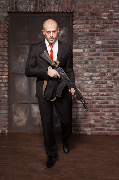 Assassin in suit and red tie holding machine gun