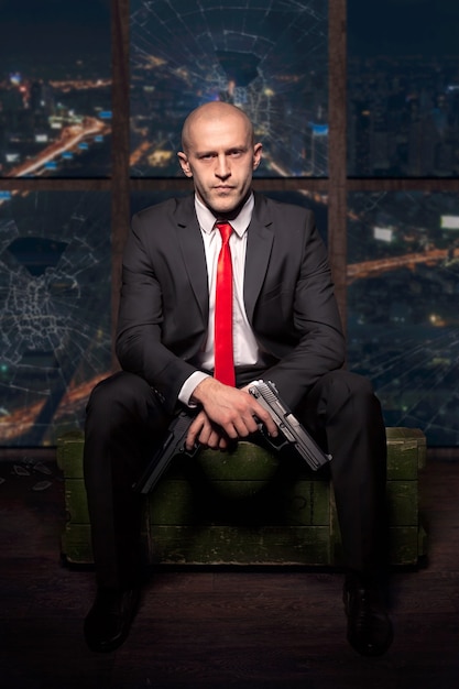 Assassin in suit and red tie holding pistol in hand