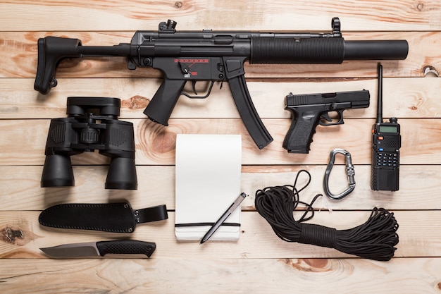 写真 アサルトライフル、銃、鞘付きナイフ、コンパス、テーブルにペンでノート。