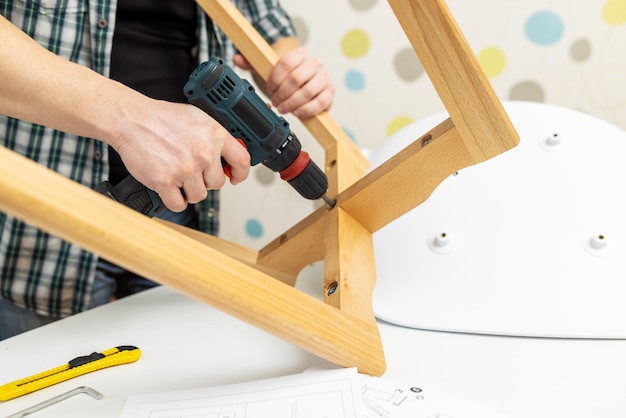 Assemble furniture man assembling chair furniture assembler with drill