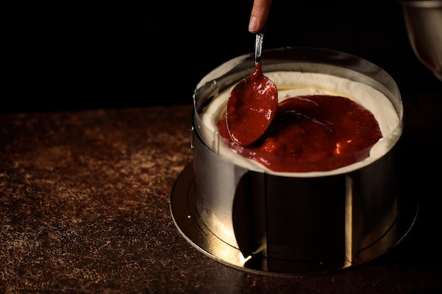 Assembling a cake in a confectionery ring on a dark background