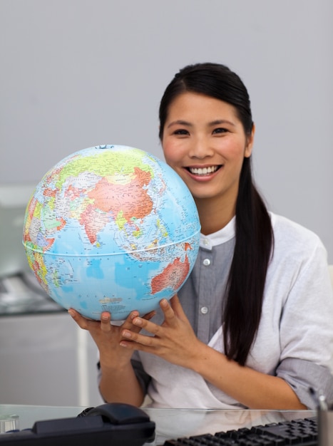 Настойчивая азиатская бизнесмен, держащая глобус