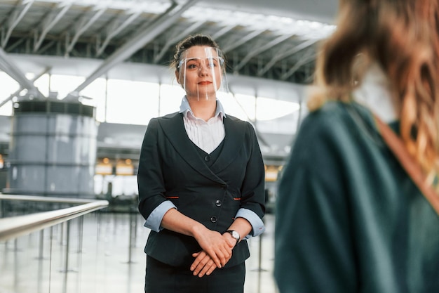 Assistance by woman in formal clothes Young female tourist is in the airport at daytime