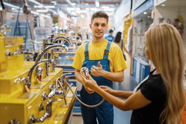 Помощник и клиентка выбирают душ в хозяйственном магазине. Продавец в униформе и женщина в магазине поделок, покупки в строительном супермаркете