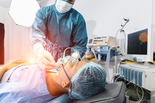 Ассистент хирурга надел пациенту респираторно-кислородную маску для подготовки к операции.