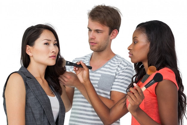 Assistants applying make-up to female model