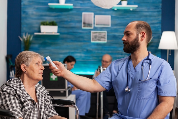 Assistent-helper die de temperatuur controleert met behulp van medische infraroodthermometer