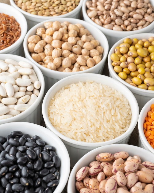 Assorted beans and grains on white bowls.