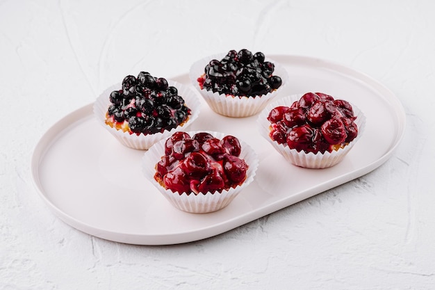 Photo assorted berry tartlets on white plate