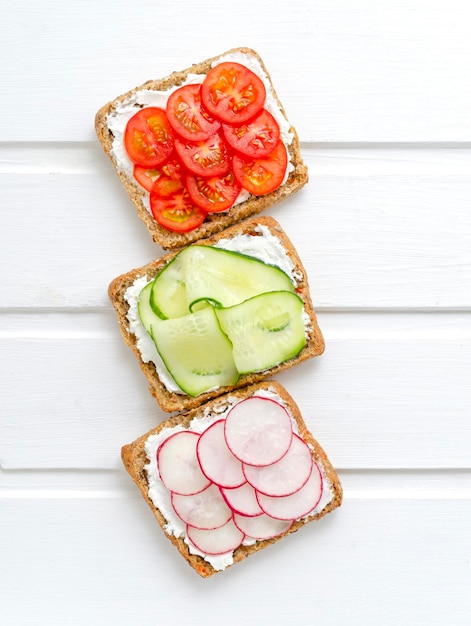 assorted breakfast sandwiches with a slice of whole grain dark bread cream cheese cucumbers