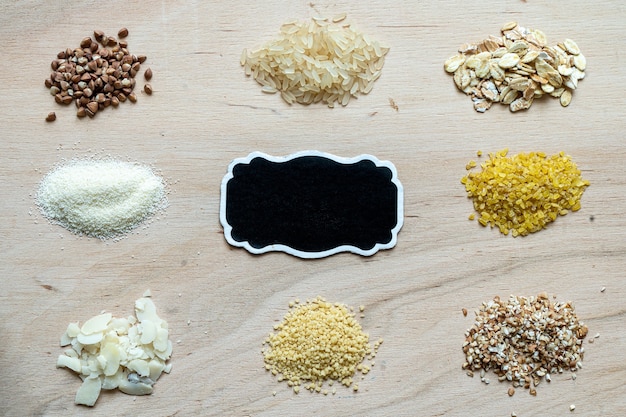 Assorted cereal grain porridge seeds set on a wooden background: buckwheat, rice, semolina, wheat, couscous, oatmeal