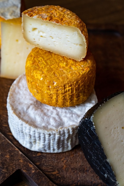 木製のテーブルのまな板に盛り合わせチーズヘッド。チーズ工場とチーズショップ。自然の農場の乳製品。広告とメニュー。