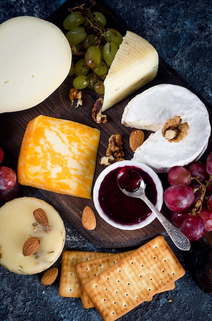 Assorted cheese pieces jam grapes cookies and nuts