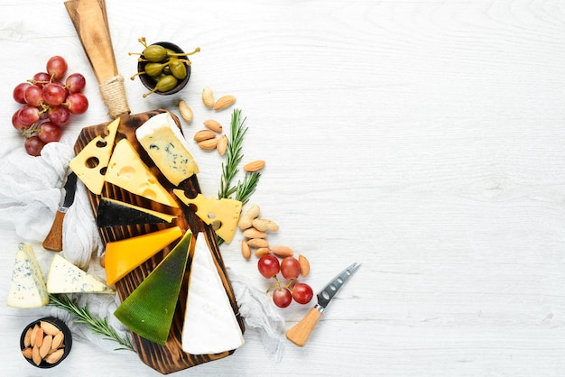 Assorted cheese and snacks on white wooden background Dairy products Top view Free space for your text