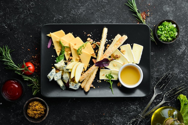 Assorted cheese with honey on a black plate Top view Free space for your text