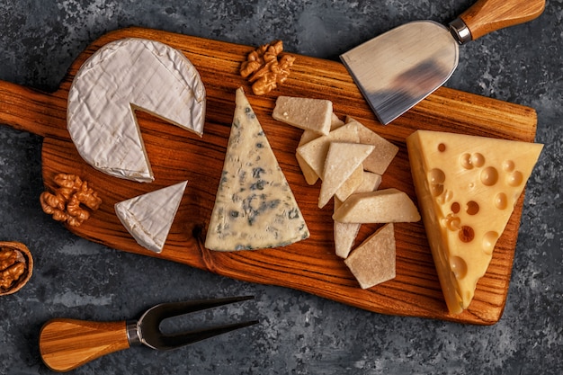 Assorted cheeses on wooden board.