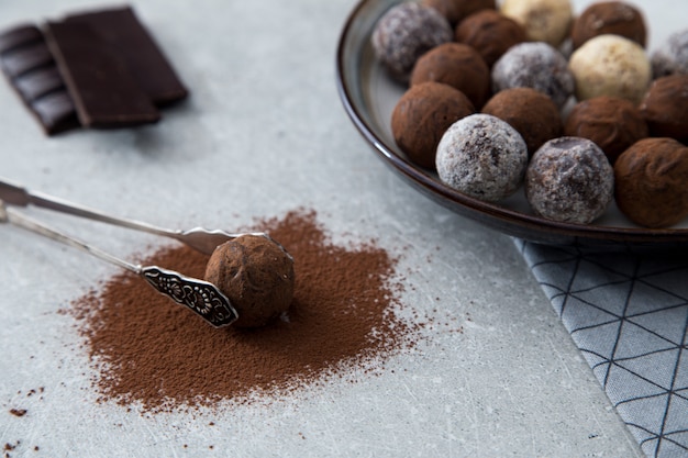 Assorted chocolate truffles with cocoa powder, coconut and chopped hazelnuts on a dessert plate