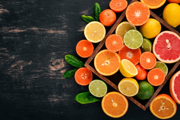 Assorted citrus fruit in a wooden box Orange tangerine grapefruit lemon On a wooden background Top view Copy space